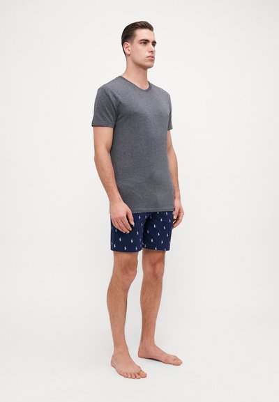 T-shirt gris à manches courtes associé à un short bleu marine à motif avec un logo blanc répété. Coupe légère et décontractée, idéale pour se détendre.
