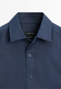 Navy blue linen button-up shirt with pointed collar and two visible buttons, labeled Massimo Dutti, made in China.