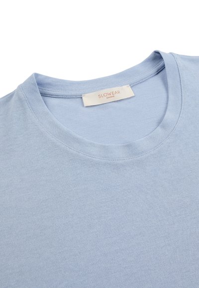 T-shirt à col rond bleu clair avec une étiquette de marque visible "SLOWEAR ZANONE" cousue à l'intérieur du col.