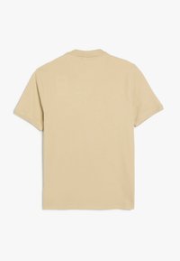 Camiseta de algodón beige de manga corta con un clásico cuello redondo, textura suave y un diseño sencillo y sin adornos.