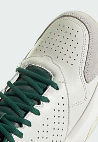 Bőrből készült sneaker, perforált bézs felsőrésszel, zöld fűzőkkel �és nubuk kiegészítőkkel. Jellemzője a textúrált talp és a párnázott nyelv.
