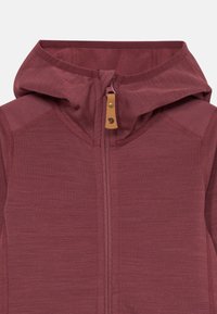 Bordo spalvota zip-up gobtuvinė striukė su odiniu užtrauktuko rankenėle, turinti logotipą, matomus siūlus ir aukštą gobtuvą.