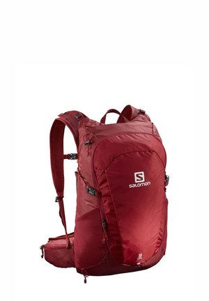 Sac à dos rouge au design épuré, fabriqué en tissu résistant. Il dispose de bretelles réglables, de compartiments zippés et d'un logo sur le devant.