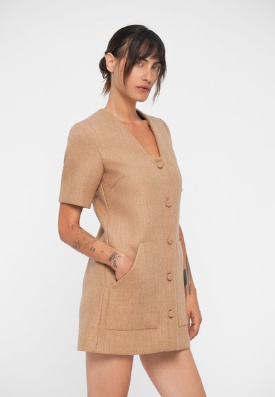 Robe courte beige à manches courtes avec un décolleté en V, fermeture à boutons sur le devant et deux poches latérales. Tissu texturé avec un motif subtil.