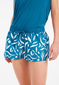 Mėlynos šortai su baltu abstrakčiu lapų ir linijų raštu, su elastinga juosmens juosta ir raišteliu. Pintas audinys ir laisvas kirpimas.