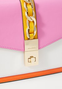 Borsa a tracolla rosa e bianca con hardware dorato, dotata di catena gialla e dettagli arancioni. Texture liscia con un design geometrico.
