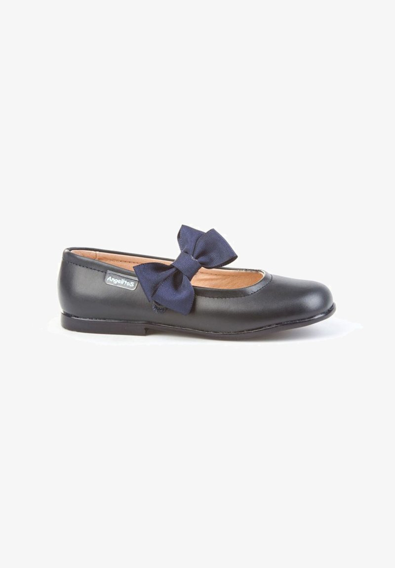 Zapato plano de cuero negro con punta redondeada y gran lazo azul marino en la parte superior, que presenta una pequeña etiqueta de la marca Angeliños en el lateral.