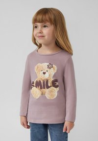 T-shirt z długim rękawem w kolorze lawendowym z grafiką jasnobrązowego misia z napisem "UŚMIECH" w połyskujących brązowych literach. Wykonany z miękkiej bawełny.