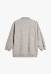 Sudadera gris de manga larga, con puños acanalados y un cuello alto. Tejido suave con una textura lisa, presenta un corte holgado.