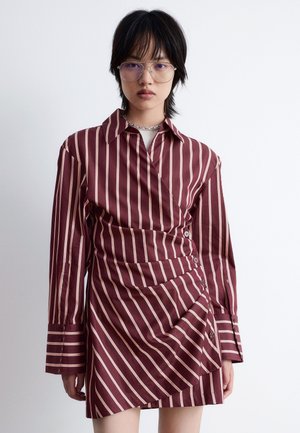 Striped shirt dress in deep burgundy and cream. Features long sleeves, button accents, and a wrap design with gathered texture.