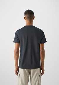 T-shirt en coton gris avec un col rond, des manches courtes et une coupe décontractée, vue de dos, mettant en avant une texture lisse.