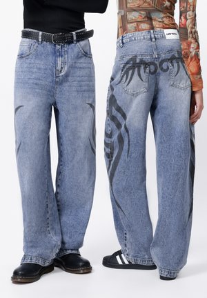 Zalige denim jeans in lichtblauw. Voorzien van zwarte tribale patronen aan de zijkanten, vijf zakken en een tailleband met riemlussen.