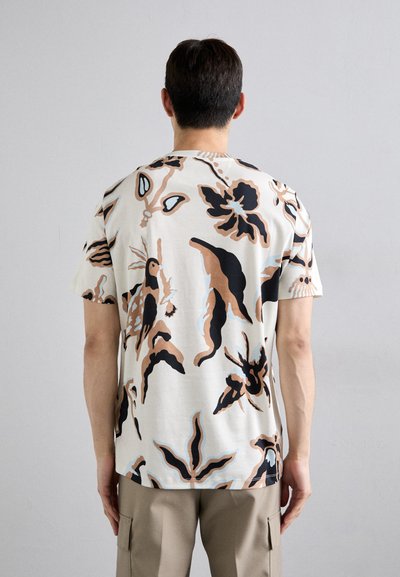 Kortærmet t-shirt i creme farve med abstrakte blomster mønstre i sort, brunt og lyseblåt; lavet af blød bomuld, afslappet pasform.