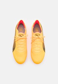 Yellow soccer shoes with black accents, smooth synthetic material, round toe, laces, and padded inner lining. Logo on the tongue.