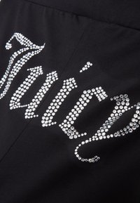 Mustmust kangas, millel on suured kristallid paigutatud sõna "Juicy" kutsuvas kirjas, rõhutades sädelevat tekstuuri ja disaini.