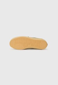 Sneaker outsole featuring a textured rubber sole with a diamond pattern, in light brown color, with a subtle grip for traction.