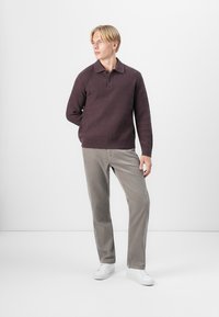Knitted dark purple pullover with a textured pattern, collared design, paired with light gray pants and white sneakers.