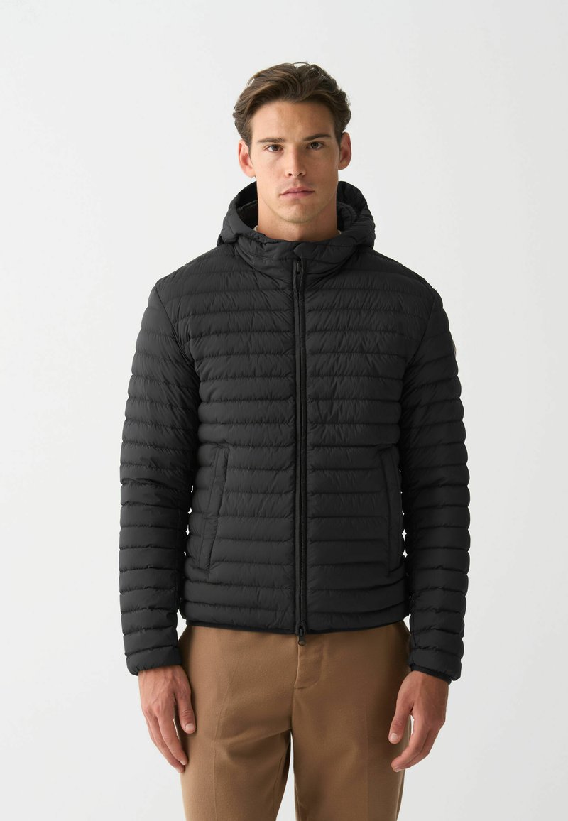 Chaqueta acolchada negra con costuras horizontales, cremallera frontal y capucha. Cuenta con bolsillos laterales y puños ajustados. Textura ligera y suave.
