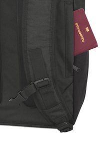 Zaino nero con spallacci regolabili, dotato di una tasca laterale che ospita un passaporto color mogano con testo dorato che dice "REISEPASS."