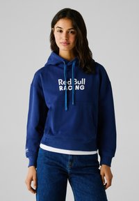 Hoodie bleu marine avec une poche kangourou, des cordons de serrage et du texte blanc "Red Bull RACING". Fabriqué en tissu doux, avec des poignets côtelés.