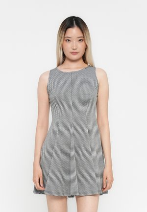 Robe sans manches à motifs vichy noir et blanc, avec un corsage ajusté et une jupe évasée, confectionnée en tissu léger.