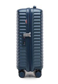 Maleta rígida de color azul marino con textura estriada, doble cremallera, candado de combinación y cuatro ruedas giratorias para facilitar la movilidad.
