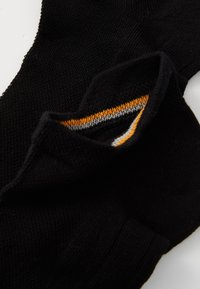 Sosete negre dintr-un material moale, cu o textură canelată, având un accent striat îngust portocaliu și gri aproape de deschidere.