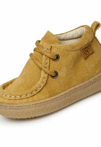 Stivaletto alla caviglia in suede giallo con punta tonda, due fori e lacci marroni, dotato di suola in gomma testurizzata e dettaglio di design cucito.