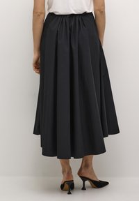 Svart midikjol i slätt tyg, med en samlad elastisk midja, plisserad design och en flytande siluett.