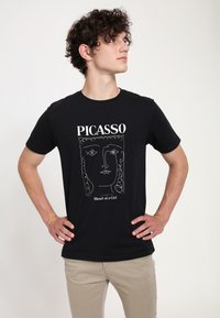 Černé bavlněné tričko s bílým liniovým obrazem tváře inspirovaným Picassem, s textem "PICASSO" a "Hlava dívky" níže.