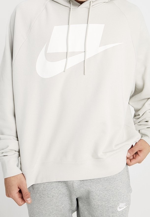Ljusgrå Nike hoodie med en stor vit logga. Har en dragsko för huvan, långa ärmar och ribbade ärmslut och nederkant. Mjuk textur.