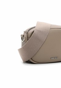 Sac bandoulière en cuir beige avec une finition texturée, doté d'une large sangle en tissu et d'un compartiment zippé avec un détail logo argenté.