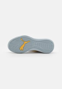 Semelle de sneaker Puma en caoutchouc gris clair, avec un logo jaune et un motif de bande de roulement en zigzag pour la traction. Texture lisse dans l'ensemble.