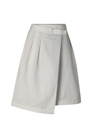 Woman wearing light gray sleeveless zippered vest, matching asymmetrical knee-length skirt, white cap, and chunky gray sneakers with pink accents.