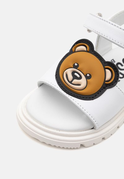 Sandalo bianco con applicazione di faccina d'orso in gomma sulla cinghia. Suola spessa con superficie texture e fibbia regolabile per una vestibilità ottimale.