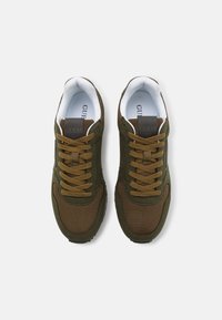 Zielono-brązowe siateczkowe sneakersy z okrągłymi noskami, brązowym sznurowaniem i szarym logo na języku. Biały wyściełany kołnierz i wkładka.