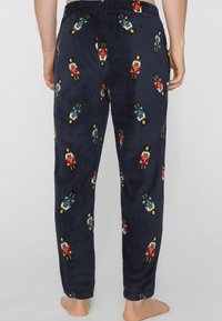 Granatowe polarowe spodnie do piżamy z kolorowymi wzorami dziadków do orzechów, ściągaczem w pasie i zwężanymi nogawkami dla luźnego dopasowania.
