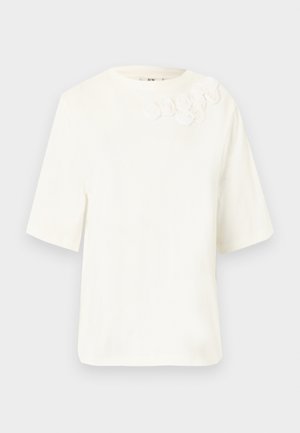 Λευκό μπλουζάκι με κοντά μανίκια και στρογγυλή λαιμόκοψη, με πέντε μικρά υφασμάτινα λουλούδια κεντημένα κοντά στον αριστερό ώμο.