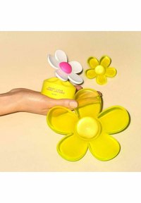 Gul blommig parfymburk med en rosa mitt, omgiven av två gula blomformade brickor. Slät plasttextur, lekfull design.