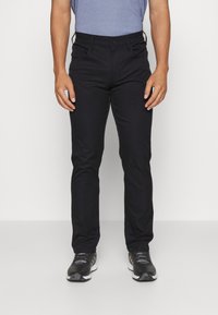 Schwarze Slim-Fit-Hose aus einem glatten Stoff mit Knopfverschluss. Verfügt über Fronttaschen und ein modernes, maßgeschneidertes Design.