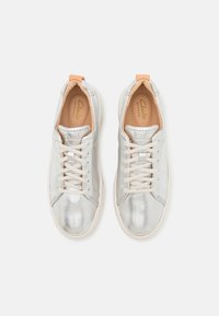 Baskets métalliques argentées à texture lisse, bout arrondi et accents beige clair. Dotées de lacets blancs et de semelles rembourrées.
