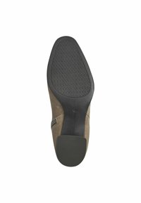 Semelle de chaussure en cuir avec un fond en caoutchouc noir texturé, dotée d'une tige en daim beige et d'un design à bout arrondi, accentuée par une fermeture éclair sur le côté.