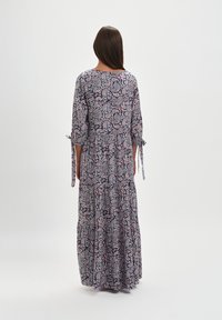 Maxi sukienka w wzór paisley w kolorach granatowym, białym i czerwonym. Rękawy o długości 3/4 z detalami w postaci związania. Zwiewny, warstwowy krój z miękkiego materiału.