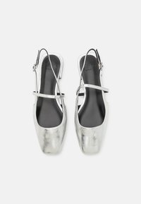 Silver metallic slingback shoes with a square toe, minimalist design, adjustable strap, and smooth texture. Inside features black branding.