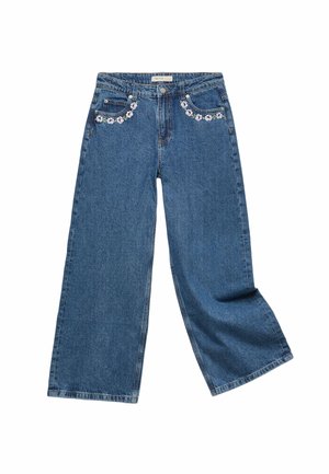 Blå vidde jeans med blomsterbroderi foran nær lommerne og lukning med knap og lynlås.