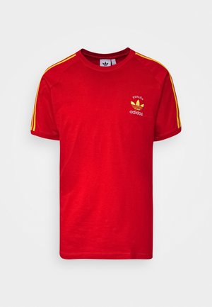 T-shirt rouge Adidas avec des rayures jaunes sur les manches et un petit logo "España" avec le trèfle Adidas sur la poitrine.