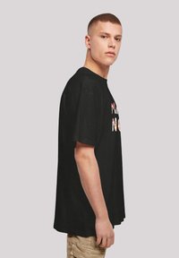 Black cotton t-shirt with short sleeves, featuring a multi-colored graphic on the front. Loose fit, round neck, minimalistic design.