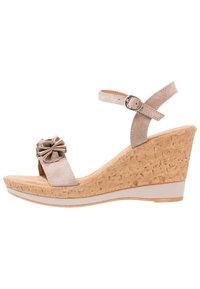 Sandalias de cuña beige con suela de corcho, correa ajustable en el tobillo y un adorno de flor de tela en la tira del dedo. Material superior similar al ante.