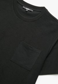 Sort bomulds T-shirt med rund hals, korte ærmer og en laplomme foran. Glat tekstur og afslappet pasform.