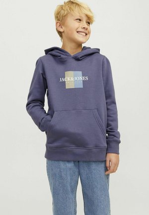 Sweat à capuche en polaire violet avec une poche kangourou, arborant un logo carré multicolore sur la poitrine. Associé à un jean en denim bleu clair.